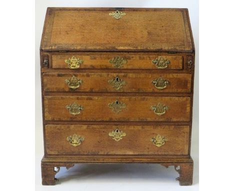 A George III oak and walnut crossbanded bureau Of typical form, the hinged sloped front opening to a interior with pigeon hol