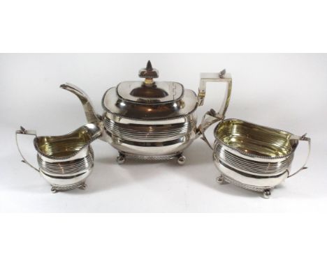 A George III silver tea setComprising a teapot, milk jug and sugar bowl, each raised on four bun feet with grooved body and s