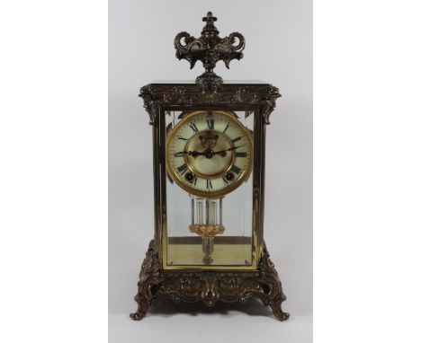 An early 20th Century Continental mantel clockThe circular face with white enamel chapter ring and Roman numerals to a brass 