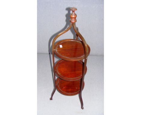 An Edwardian mahogany three tiered cake stand with an ornate finial top.   CONDITION REPORT:  In good condition.