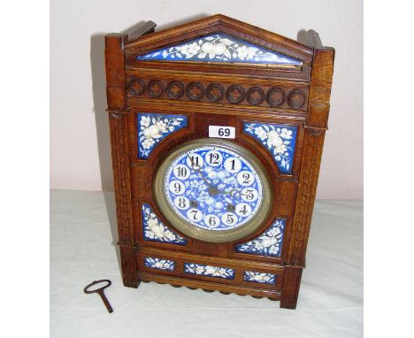 A mantle clock, made from carved oak, measuring 17.5" tall, with a blue floral style dial.    CONDITION REPORT:  Missing its 