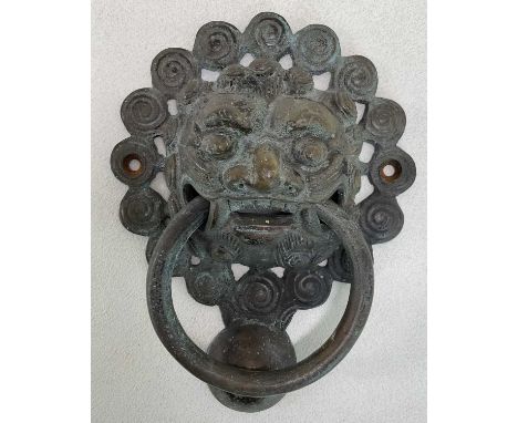 A Chinese bronze door knocker, with raised mask ring loop and pierced back plate, length approx 23cm.