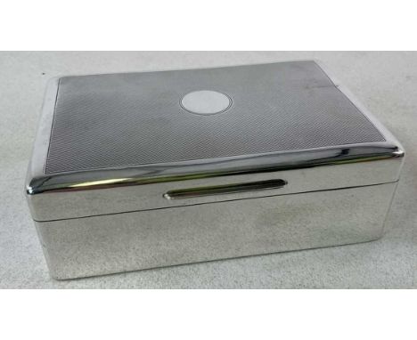 An early 20th century hallmarked silver clad cigarette box, with vacant roundel to the engine turned decorated lid, marks obs
