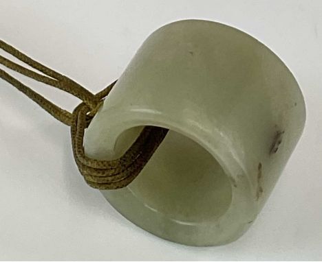 A Chinese jade archer's ring, probably 18th century, with remnants of thread still attached, diameter 28mm, width 24mm.