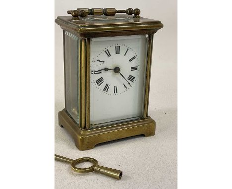A circa 1900 French brass carriage clock, with Roman numerals to the white enamel dial, height with handle flat 11.5cm.