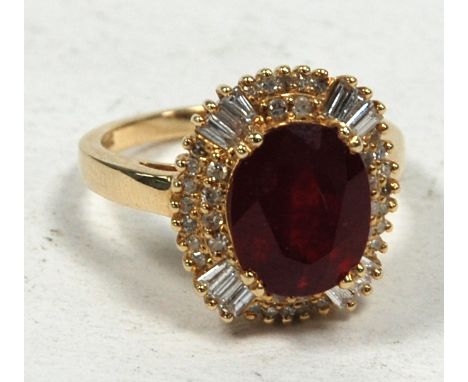 14k YELLOW GOLD AND DIAMOND RING, set with an oval cut ruby approx 5.40ct, the wavy surround set with two radiating baguette 