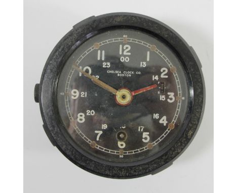 A US Army M1 Message Center bulkhead clock, the 10cm circular black enamel dial with luminous hands, lacking centre sweep sec