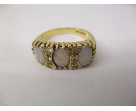 An 18ct gold ring set with three opals and six diamonds in a claw setting, with engraved shoulders, size P, 7.5g 