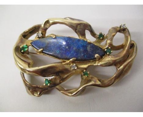 A gold coloured metal organic style brooch, possibly American, set with a lozenge shaped opal doublet, five emeralds and thre