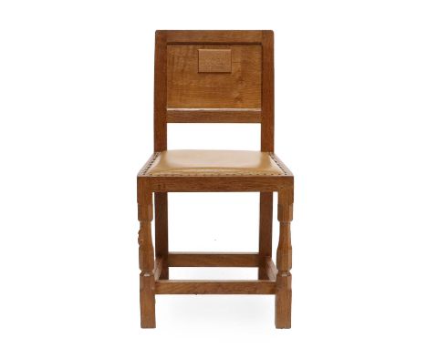 Workshop of Robert Mouseman Thompson (Kilburn): An English Oak Panel Back Dining Chair, upholstered leather seat, on two octa