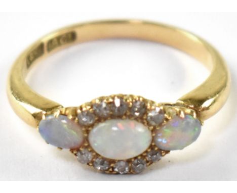 An 18ct gold diamond and opal cluster ring, the head set with a central opal surrounded with ten small diamonds flanked by tw