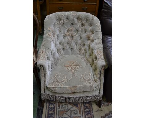 An Edwardian button back, scroll armed fireside chair.