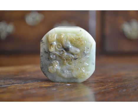 A Chinese jade canted square seal, carved in relief with a dragon amongst scrolling clouds, 5cm wide