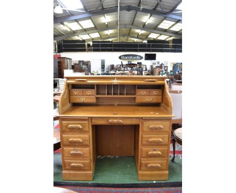 A contemporary light oak roll top pedestal desk.