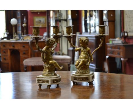 Clodion, after, a pair of gilt bronze figural two-light mantel candelabra, cast as scantily clad putti, detachable nozzles, a