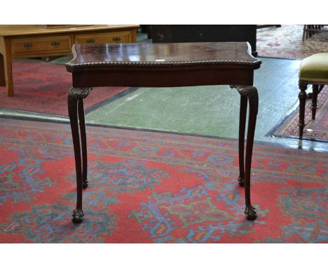 A George III Revival mahogany serpentine card table, folding top with gadrooned border enclosing an inset baize lined playing