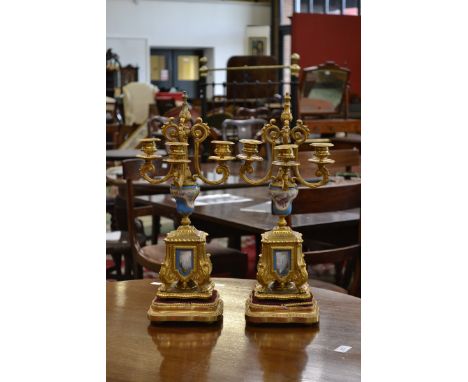A pair of French Louis XVI Revival gilt metal and porcelain four-light candelabra, fluted lotus grasped knop finials, compres