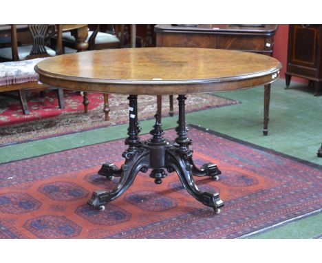 A Victorian burr walnut oval centre table, moulded tilting top, turned and carved quatre-columnar base, angular scroll feet, 