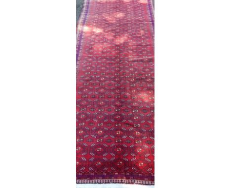 A Blooch Iranian carpet, upon red ground with blue border detail, 280 x 110cm.