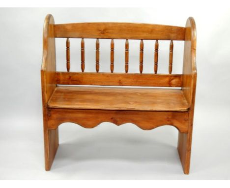 A small pine bench seat, with spindle back and shaped flat end supports, 92cm wide.