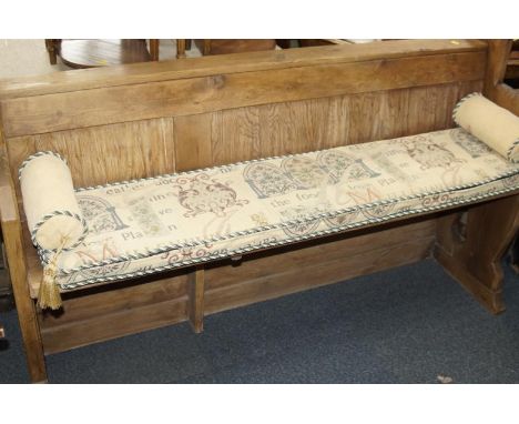 A pine bench seat, with panelled back with a loose tapestry cushion, 153cm wide.