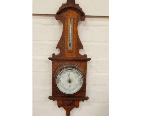 A 1930's oak aneroid barometer, having cream dial with brass surround and integral thermometer, 56cm high.