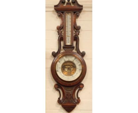 An Edwardian walnut aneroid barometer, having exposed mechanism with ceramic reader with decorative scrollwork, signed David 