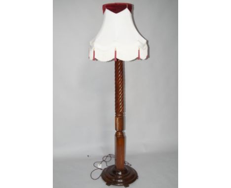 A mahogany bed post floor lamp, with spiral turned column and mounted on a raised turned circular base with low feet, and a s