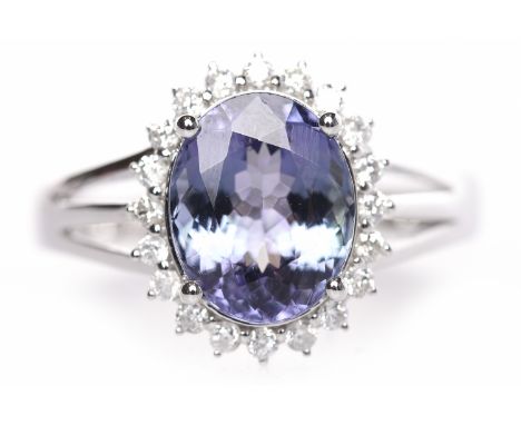 TANZANITE AND DIAMOND CLUSTER RINGset with an oval tanzanite of approximately 2.84 carats surrounded by a halo of round brill