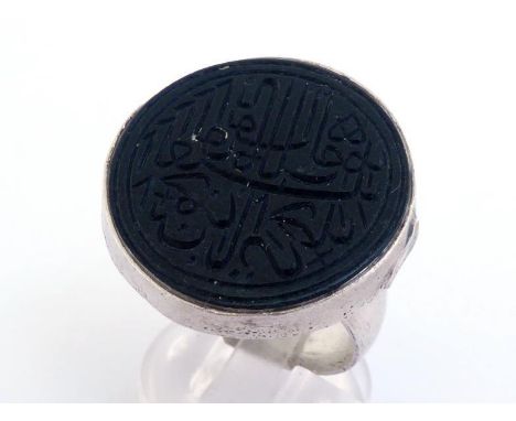 A Middle Eastern white metal (tests silver) and hardstone ring, the black circular intaglio cut with Arabic text, 25mm diamet