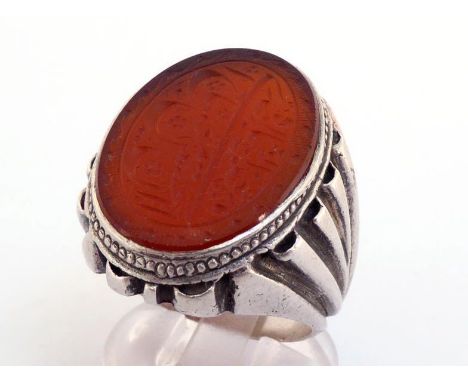 A Middle Eastern white metal (tests silver) and hardstone ring, the oval carnelian intaglio cut with Arabic text,  24 x 18mm 