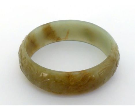 A Chinese jade bangle with beautiful chasing dragon engraving around, jade in pale celadon and brown tone, 19th/20th century,