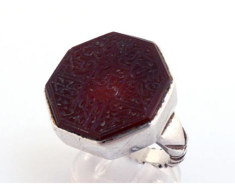 A Middle Eastern white metal (tests silver) and hardstone ring, the octagonal carnelian intaglio cut with Arabic text,  22mm 