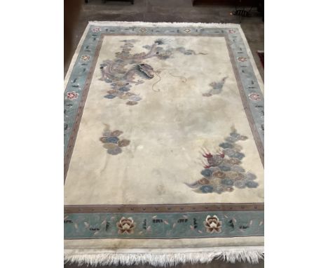 A Chinese gold ground carpet woven with dragon and flaming pearl motif within a geometric floral border, 380 x 270cm