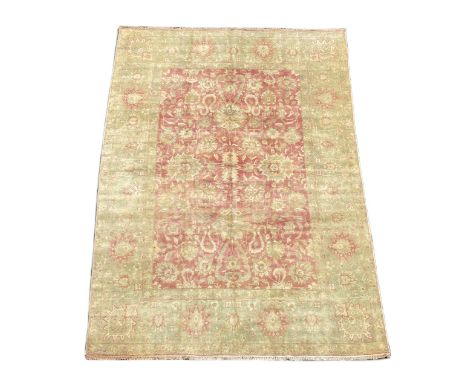 An Indian Agra carpet, with central field of stylised floral motifs on a red ground within a triple pale green and gold flora