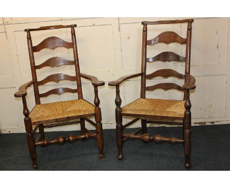 A pair of oak ladder back armchairs with rush seats, on turned supports
