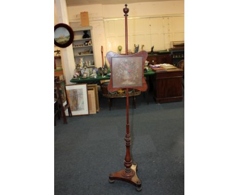 A Victorian mahogany adjustable fire screen with floral needlework panel in glazed frame, on baluster turned stem and tripod 