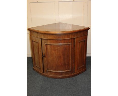 A mahogany bow front corner cabinet with panel door enclosing shelf, on plinth base, 92.5cm