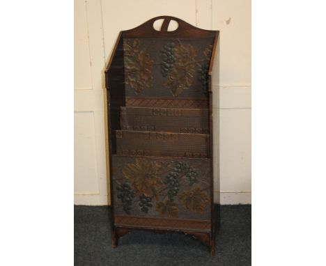 An  early 20th century oak newspaper rack, three divisions, decorated with fruiting vines, label on reverse, George Gray, Sou