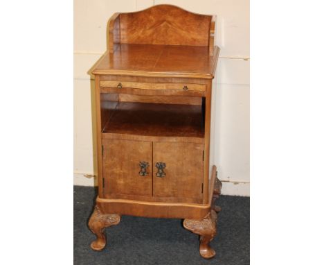 A walnut serpentine bedside table with raised three-quarter gallery back and cross-banded top above pull-out slide and shelf,