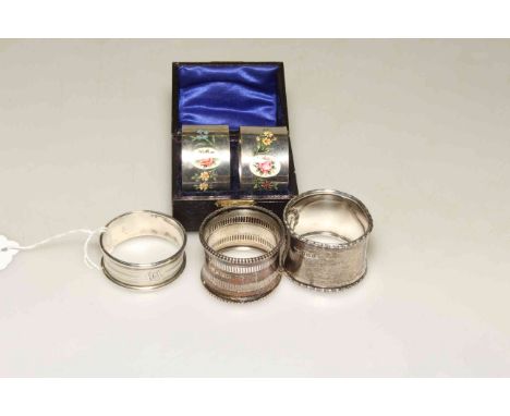 Pair of silver and enamel napkin rings, boxed; and three further napkin rings