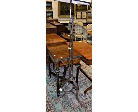 A wrought iron telescopic standard lamp in the Arts &amp; Crafts style, raised on a shaped tripod base to scroll feet