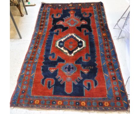 A Caucasian rug, the central panel set with central medallion on a dark red and blue ground, within a stepped geometric and s