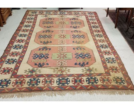 A Caucasian rug, the central panel set with three lozenge shaped medallions on a cream ground, within a stepped pink and crea