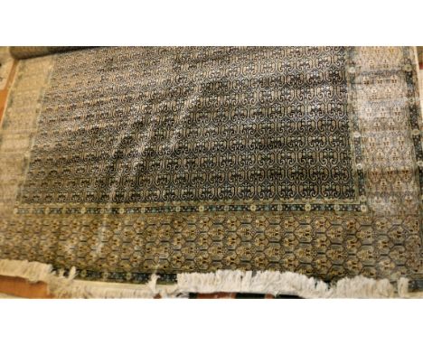 A modern fine silk Persian rug, the central panel set with repeating stylised hook moitifs within a dark blue ground within a