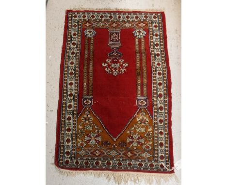 A Bokhara rug the central panel set with Mirhab style design on a red ground within a stepped red, cream and brown stylised f
