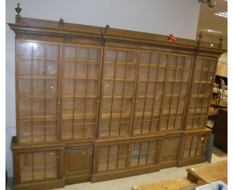 A large oak framed breakfront bookcase cabinet in the Arts and Crafts taste with six glazed and barred doors enclosing shelvi