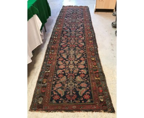 A Turkish runner, the central panel set with repeating floral motifs on a dark blue ground within a stepped red and blue flor