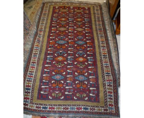 A Shirvan rug, the central panel set with repeating motifs on a dark red ground within a stepped mustard, dark red and blue b