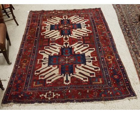 A Caucasian rug, the central panel set with stylised medallions on a red ground within a stepped red and blue geometric patte